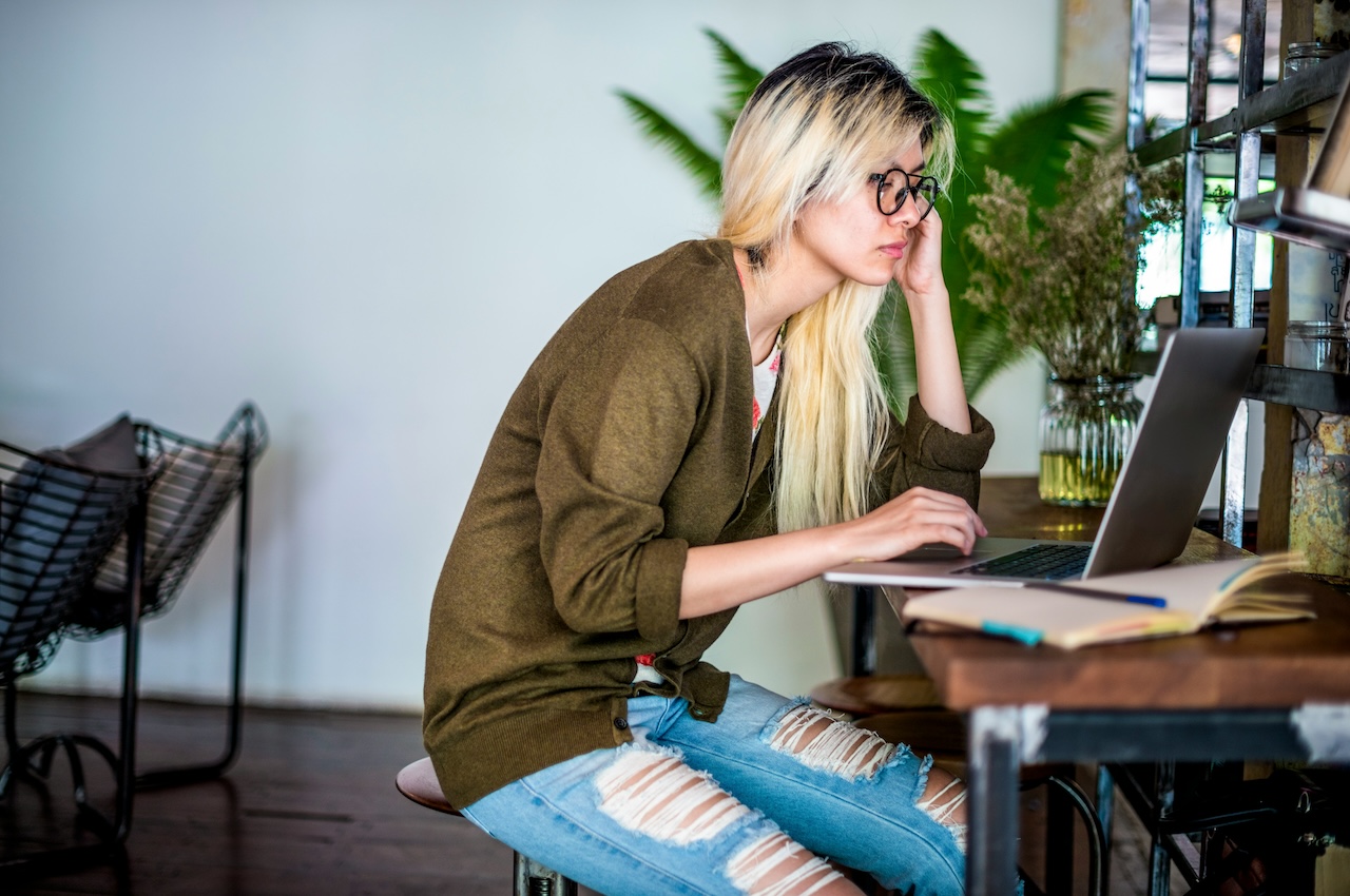 A woman sitting a desk looking at a laptop.